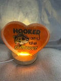 Small resin heart orange with “Hooked on The Outdoors “