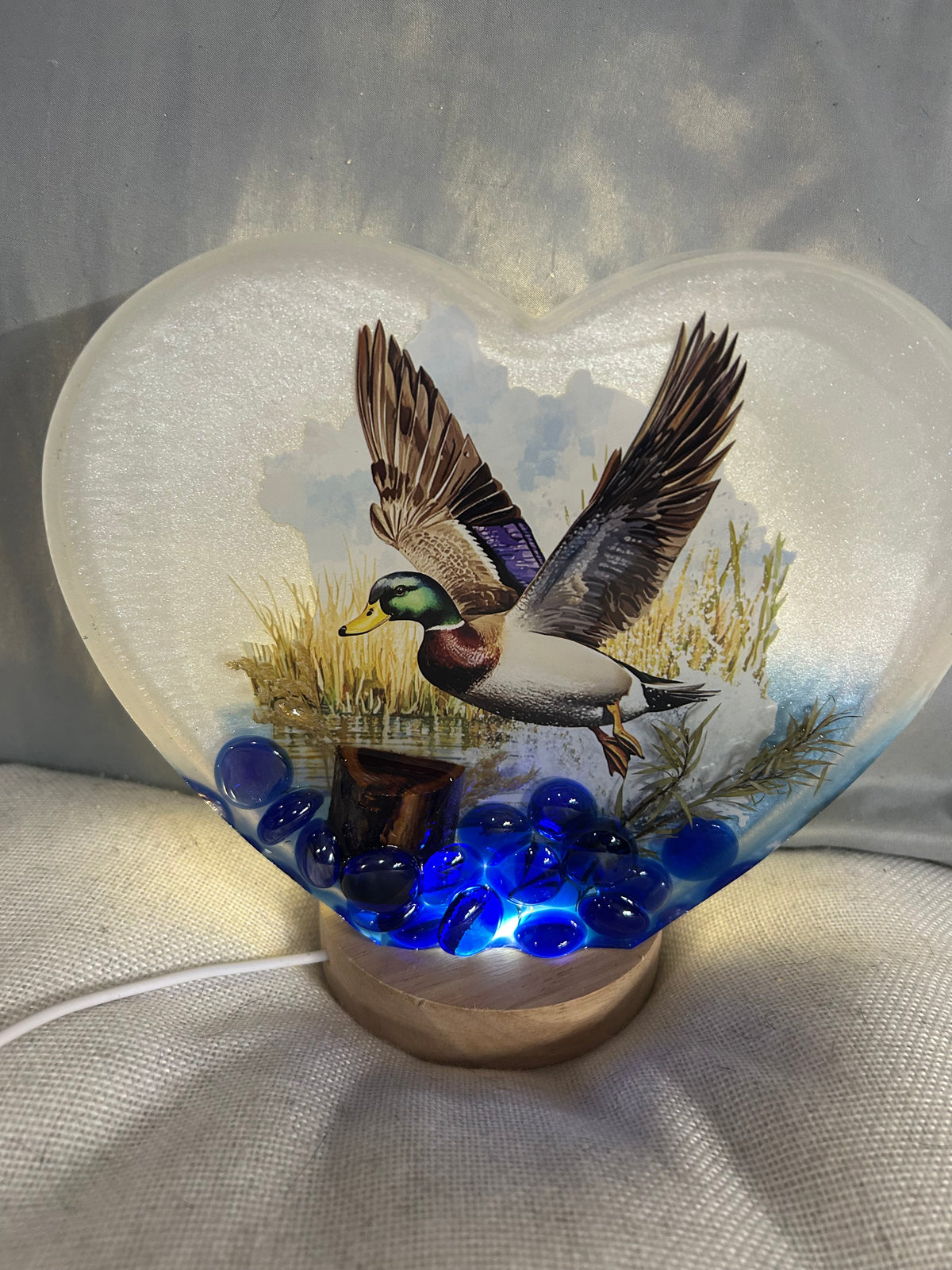 Large lighted white flying mallard duck with pond scene